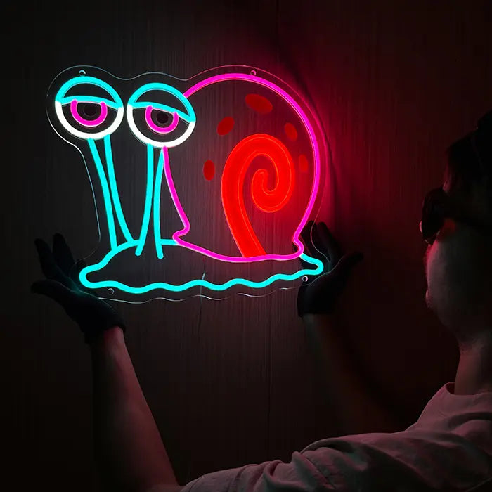 Gary Schnecke Neon LED Schild wird an eine dunkle Wand gehalten und ausgerichtet