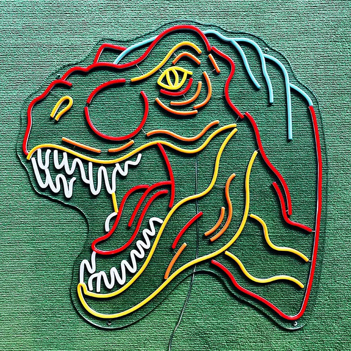 T-Rex Dino Neon LED Schild ausgeschaltet auf grünem Untergrund, komplette Kontur erkennbar