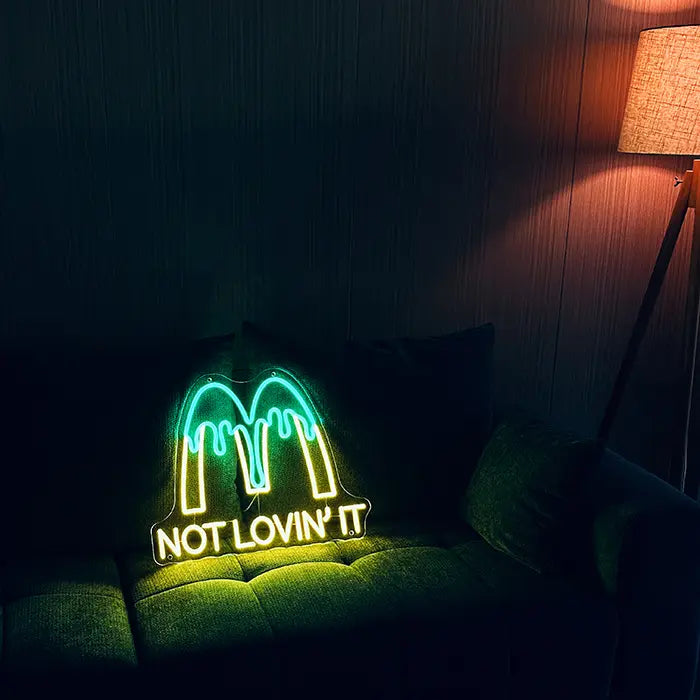 McDonald's Not Lovin' It Neon LED Schild auf einem dunklen Sofa aufgestellt, daneben eine Stehlampe