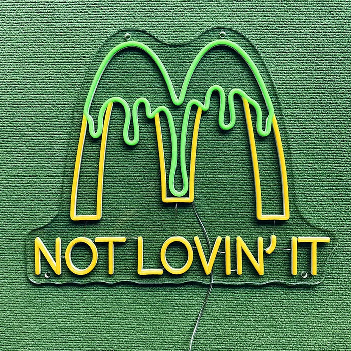 McDonald's Not Lovin' It Neon LED Schild ausgeschaltet auf grünem Untergrund, komplette Kontur erkennbar