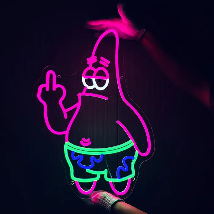 Patrick Mittelfinger Neon LED Schild wird mit Handschuhen an eine dunkle Wand gehalten