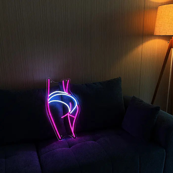 Sexy Boogie Neon LED Schild auf einem dunklen Sofa aufgestellt, daneben eine Stehlampe