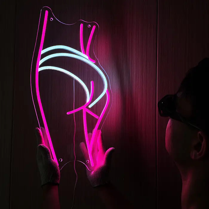 Sexy Boogie Neon LED Schild wird an der Wand ausgerichtet, eine Person hält es seitlich fest