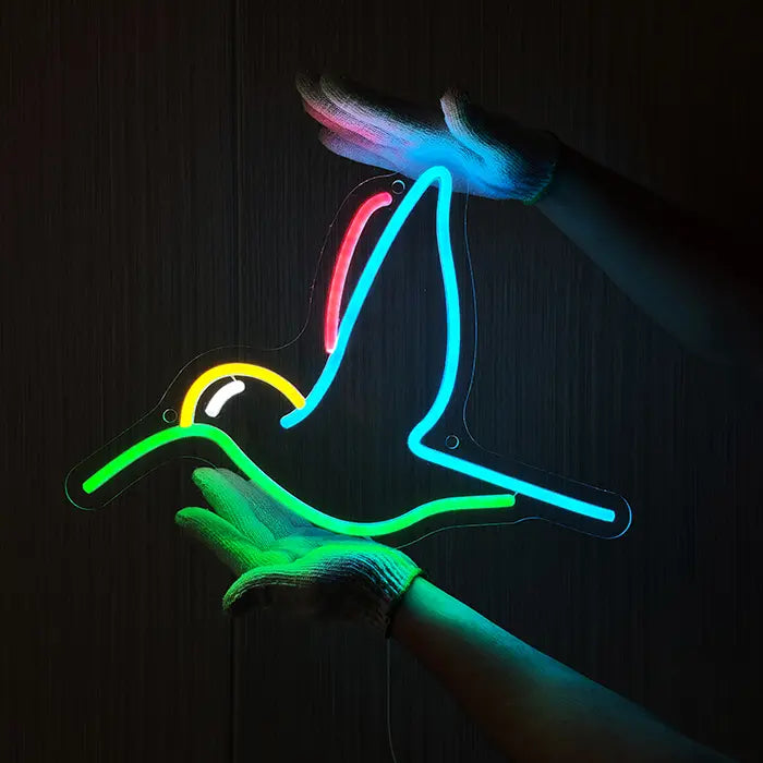Kolibri Vogel Neon LED Schild wird mit Handschuhen an eine dunkle Holzwand gehalten