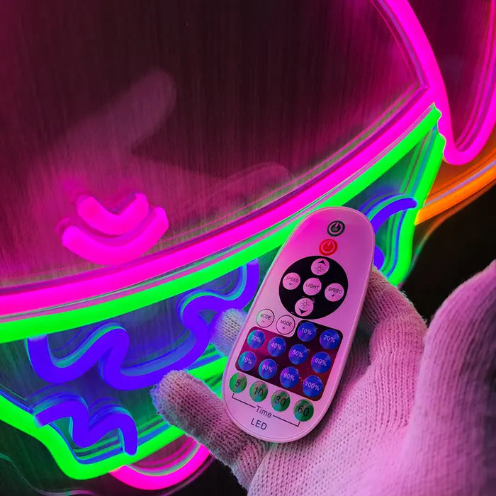 Patrick Surfer Neon LED Schild Nahaufnahme der Badeshorts, davor die Dimmer-Fernbedienung in der Hand