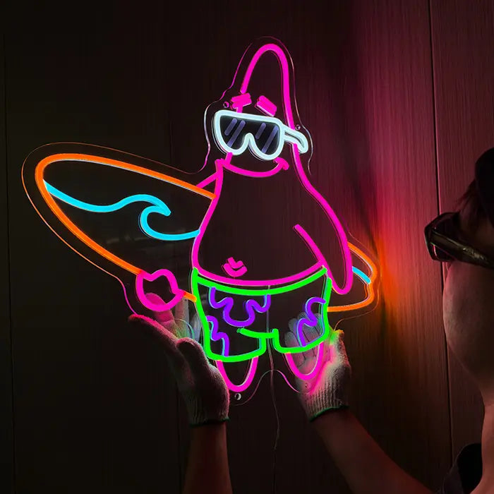 Patrick Surfer Neon LED Schild schräg von der Seite an einer Holzwand, mit Handschuhen gehalten