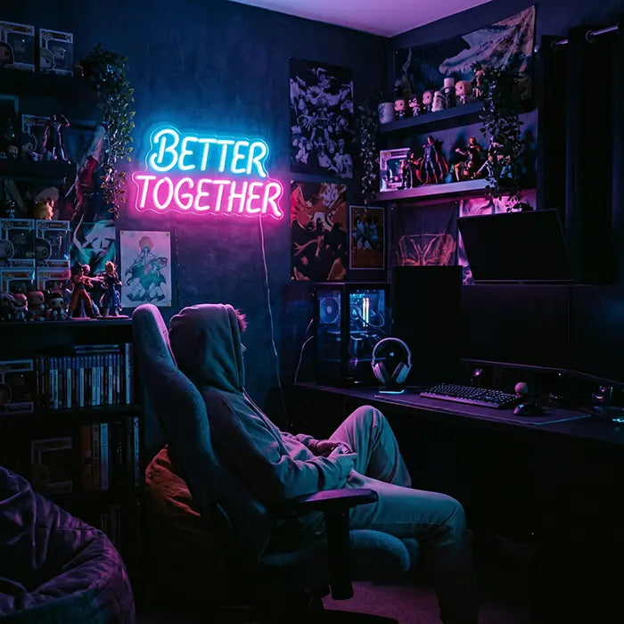 Better Together Neon LED Schild in Blau-Pink in einem Gaming-Zimmer mit Figurenregalen, davor eine Person im Gaming-Stuhl