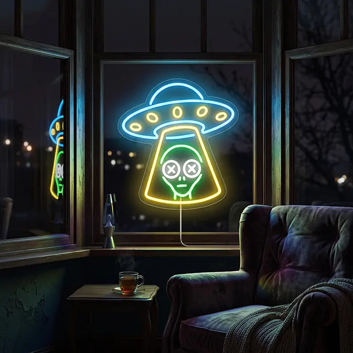 UFO Alien Entführung Neon LED Schild in einem Fenster, davor ein Sessel mit Decke und eine Tasse Tee
