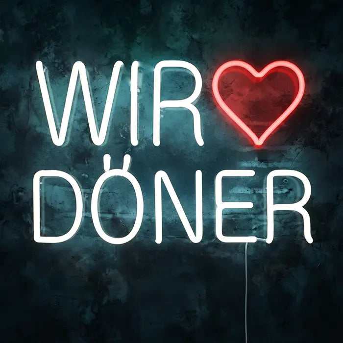 Wir lieben Döner Neon LED Schild frontal an dunkler Wand, weißer Schriftzug WIR DÖNER mit rotem Herz