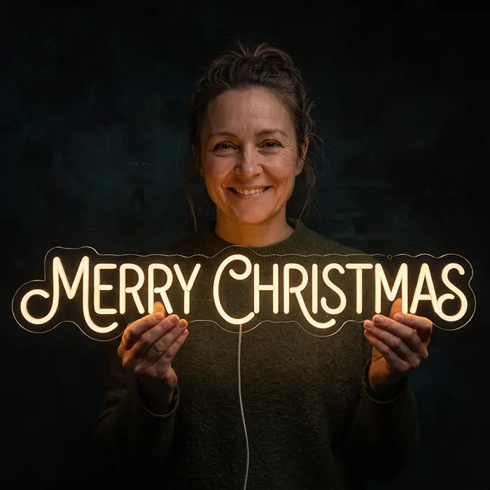Merry Christmas Neon LED Schild von einer lächelnden Person vor den Körper gehalten