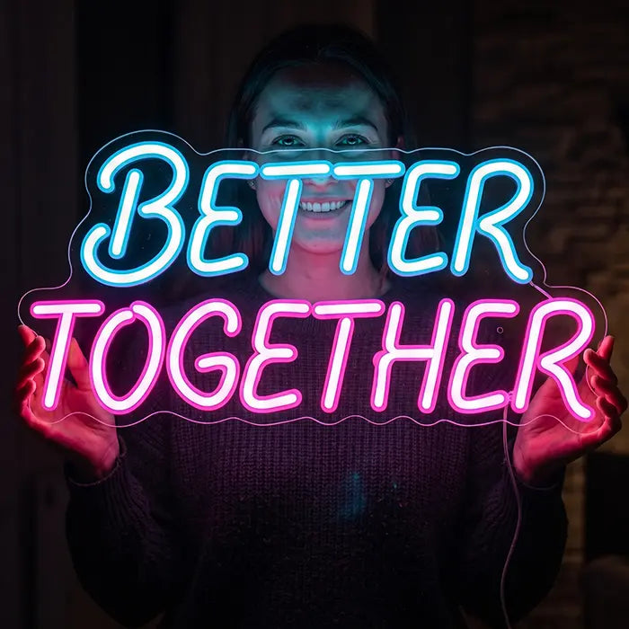 Better Together Neon LED Schild in Blau-Pink von einer lächelnden Frau gehalten