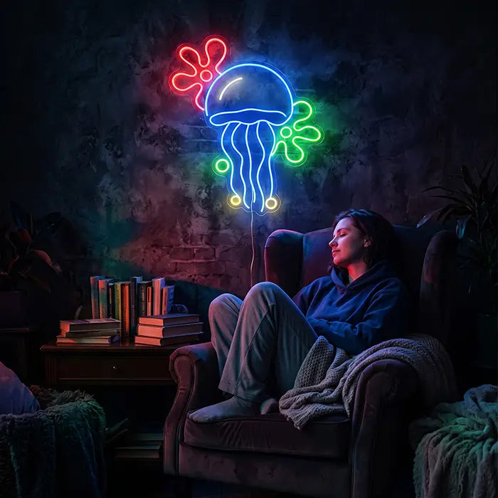 Qualle mit Blumenwolken Neon LED Schild an der Wand über einer Person, die entspannt im Sessel sitzt, daneben ein Bücherstapel