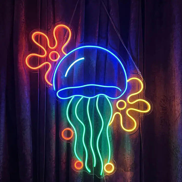 Qualle mit Blumenwolken Neon LED Schild in der Farbversion Blau-Grün vor dunklem Vorhang, mit roter und gelber Blumenwolke