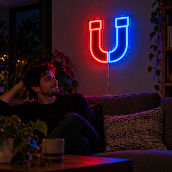Anziehungskraft Neon LED Schild an der Wohnzimmerwand, davor entspannt eine Person auf dem Sofa