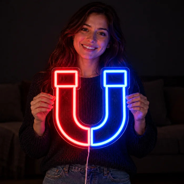 Anziehungskraft Neon LED Schild in den Händen einer lächelnden Frau vor dunklem Hintergrund