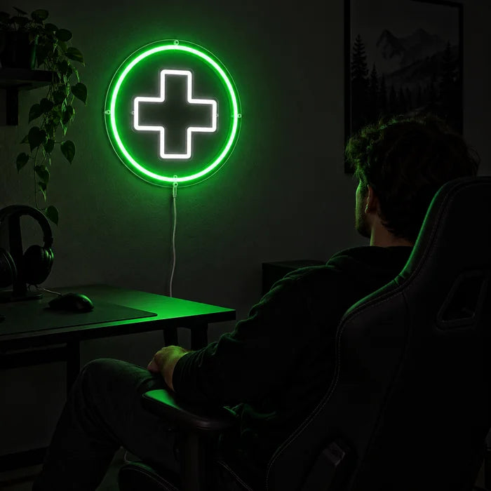 Apothekenkreuz Neon LED Schild über dem Gaming-Schreibtisch, davor ein Spieler im Gaming-Stuhl