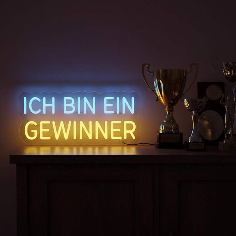 Nahaufnahme eines ästhetischen Neon-Lichtzeichens auf einem dunklen Hintergrund, das Motivation und Erfolg ausstrahlt.
