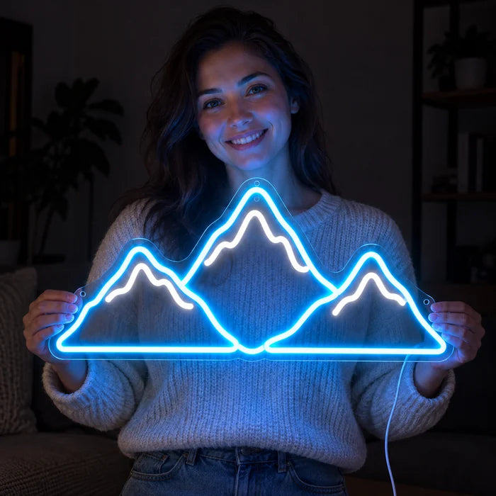 Bergsilhouette Neon LED Schild in den Händen einer lächelnden Frau vor dunklem Hintergrund