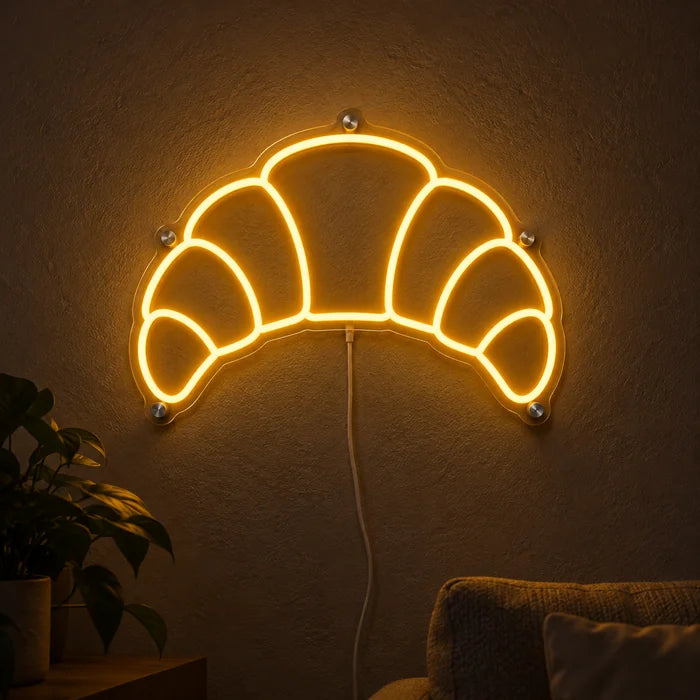 Buttercroissant Neon LED Schild leuchtend an einer dunklen Wand, Nahaufnahme mit Anschlusskabel