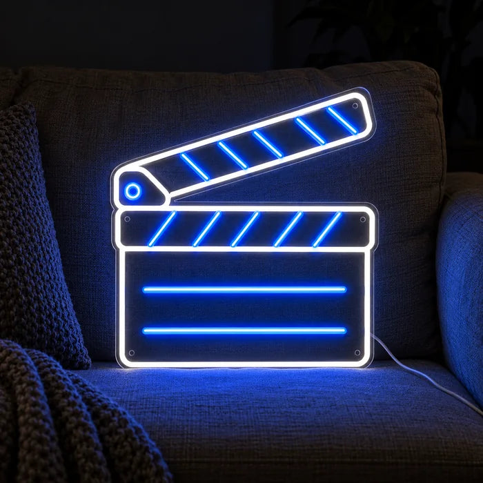 Filmklappe Neon LED Schild auf einem gemütlichen Sofa zwischen Kissen und Decke