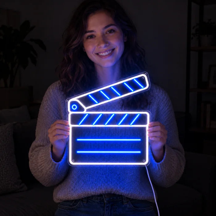 Filmklappe Neon LED Schild in den Händen einer lächelnden Frau vor dunklem Hintergrund