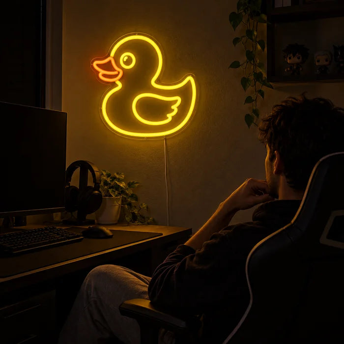 Gelbe Ente Neon LED Schild über dem Gaming-Schreibtisch, davor ein Spieler im Gaming-Stuhl