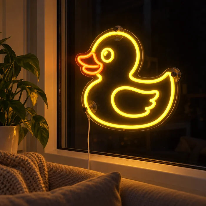 Gelbe Ente Neon LED Schild abends im Fenster eines gemütlichen Wohnzimmers