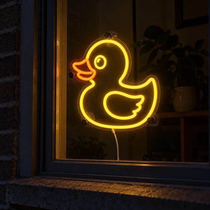 Gelbe Ente Neon LED Schild im Fenster, von der nächtlichen Straße aus gesehen