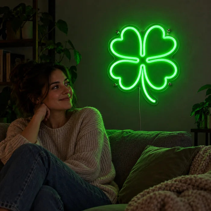 Glücksklee Neon LED Schild an der Wohnzimmerwand, davor entspannt eine Person auf dem Sofa