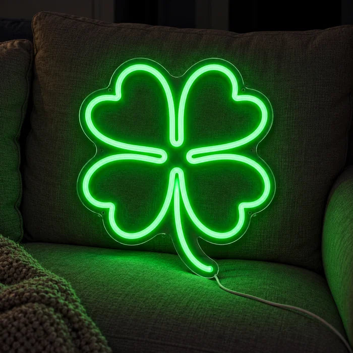 Glücksklee Neon LED Schild auf einem gemütlichen Sofa zwischen Kissen und Decke