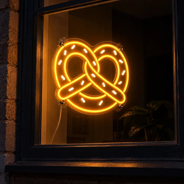 Goldene Brezel Neon LED Schild im Fenster, von der nächtlichen Straße aus gesehen
