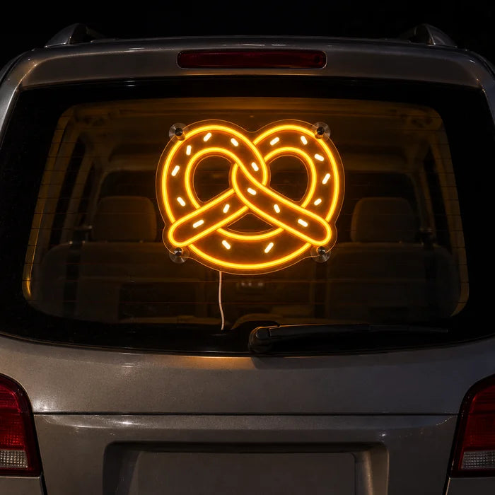 Goldene Brezel Neon LED Schild an der Heckscheibe eines Autos bei Nacht