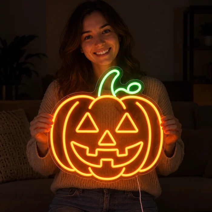 Halloween-Kürbis Neon LED Schild in den Händen einer lächelnden Frau vor dunklem Hintergrund