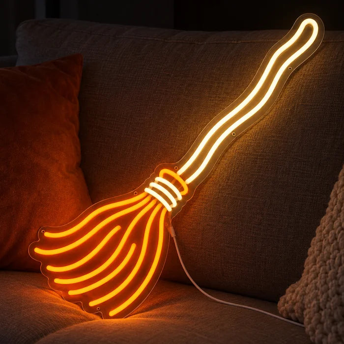 Hexenbesen Neon LED Schild auf einem gemütlichen Sofa zwischen Kissen und Decke