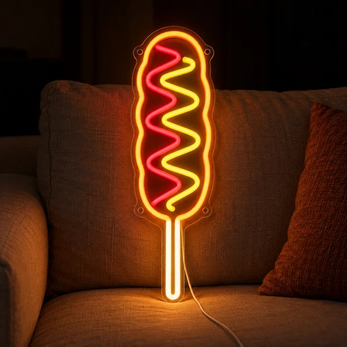 Hotdog am Stiel Neon LED Schild auf einem gemütlichen Sofa zwischen Kissen und Decke