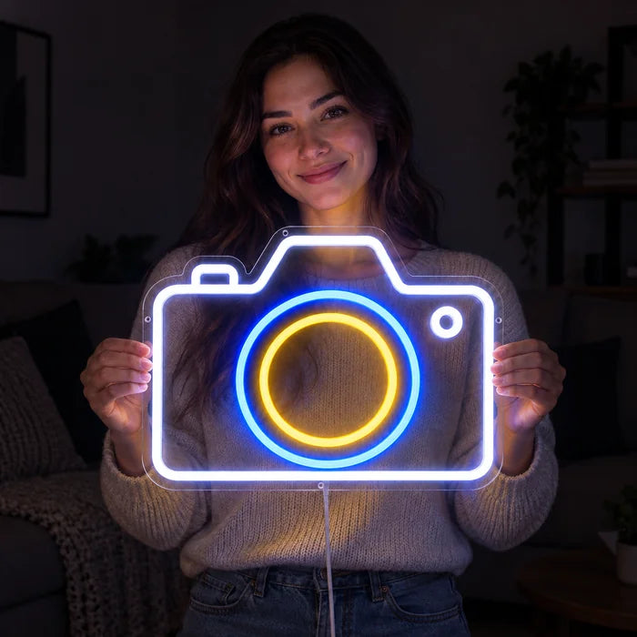 Kamera Neon LED Schild in den Händen einer lächelnden Frau vor dunklem Hintergrund