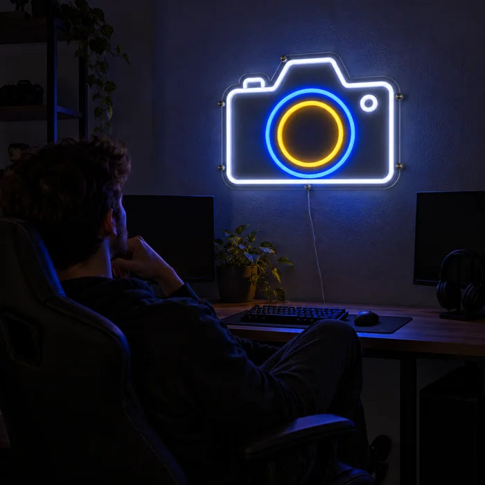 Kamera Neon LED Schild über dem Gaming-Schreibtisch, davor ein Spieler im Gaming-Stuhl