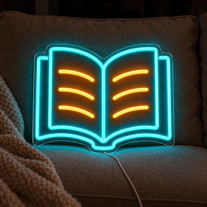 Lesebuch Neon LED Schild auf einem gemütlichen Sofa zwischen Kissen und Decke