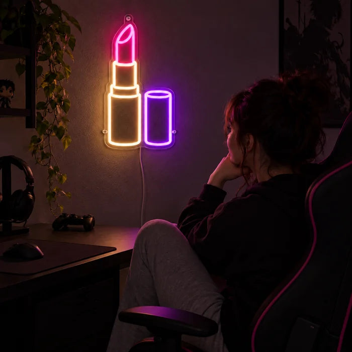 Lippenstift Neon LED Schild über dem Gaming-Schreibtisch, davor ein Spieler im Gaming-Stuhl