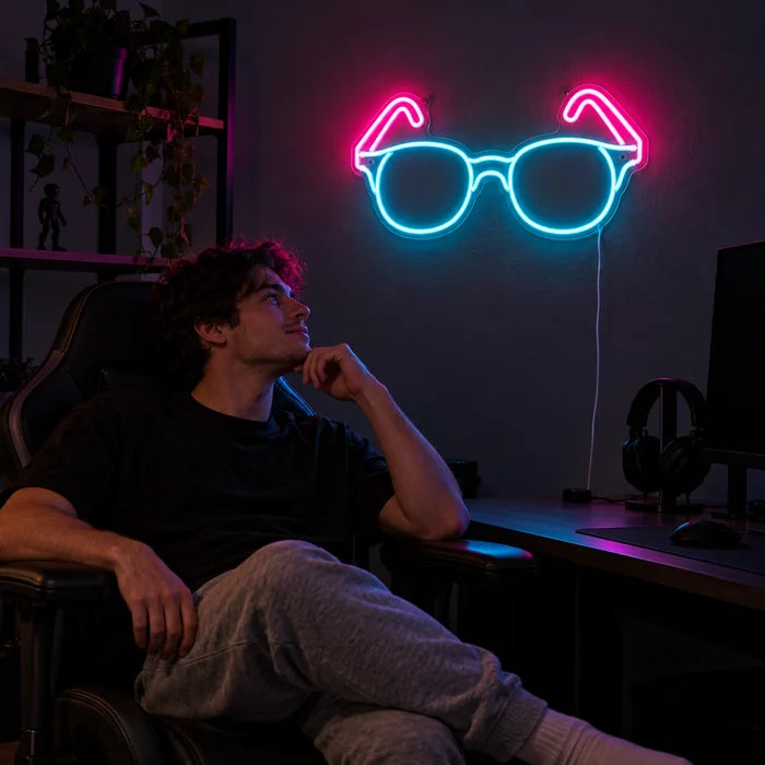Neon-Brille Neon LED Schild über dem Gaming-Schreibtisch, davor ein Spieler im Gaming-Stuhl