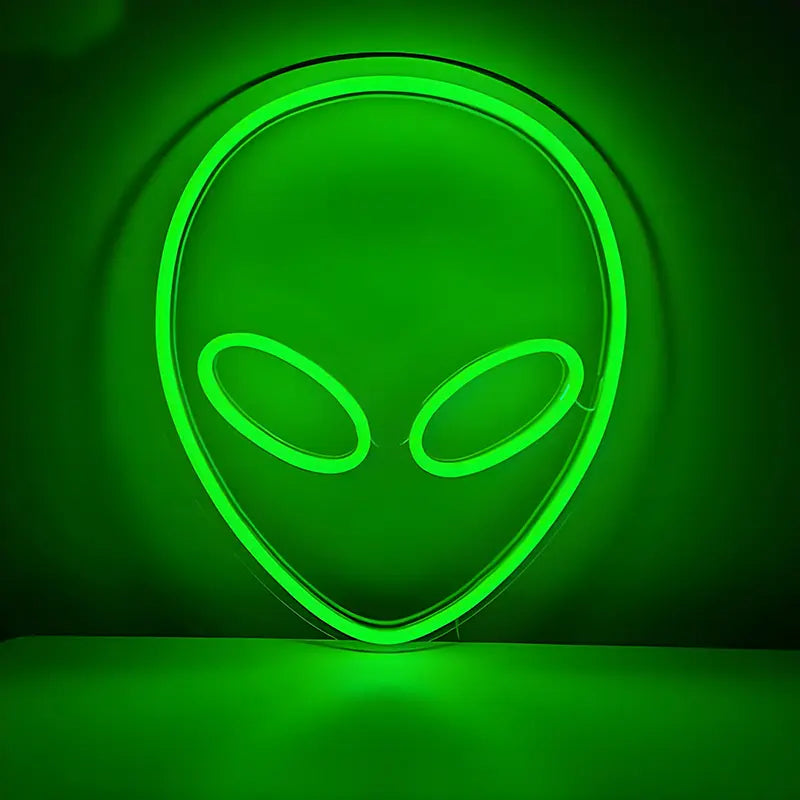 Neon-Schild in der Form eines Alien-Kopf-Umrisses, leuchtend in hellem Grün vor einer dunklen Wand.