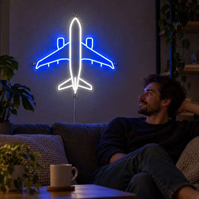 Passagierflugzeug Neon LED Schild an der Wohnzimmerwand, davor entspannt eine Person auf dem Sofa