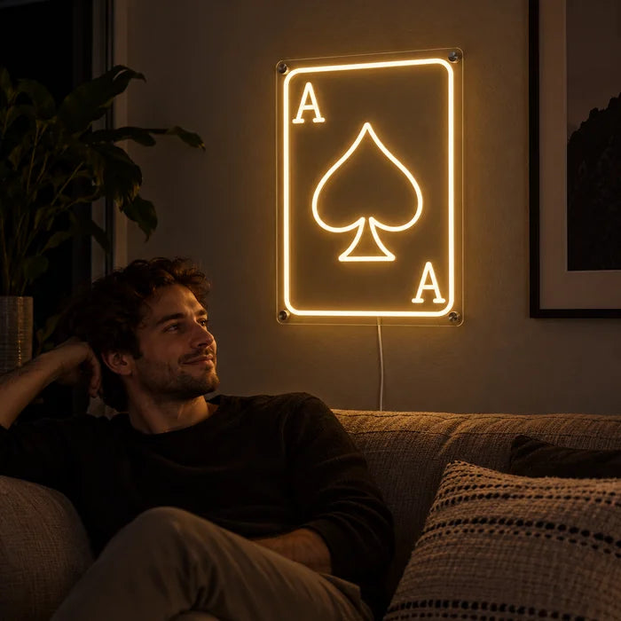 Pik-Ass Neon LED Schild an der Wohnzimmerwand, davor entspannt eine Person auf dem Sofa