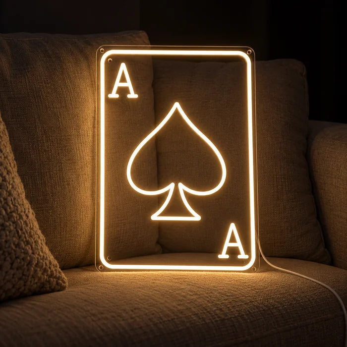 Pik-Ass Neon LED Schild auf einem gemütlichen Sofa zwischen Kissen und Decke