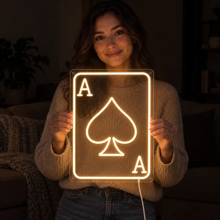 Pik-Ass Neon LED Schild in den Händen einer lächelnden Frau vor dunklem Hintergrund