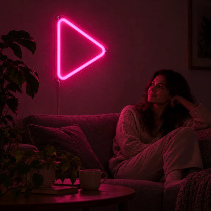 Play Neon LED Schild an der Wohnzimmerwand, davor entspannt eine Person auf dem Sofa