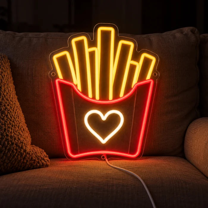 Pommesliebe Neon LED Schild auf einem gemütlichen Sofa zwischen Kissen und Decke