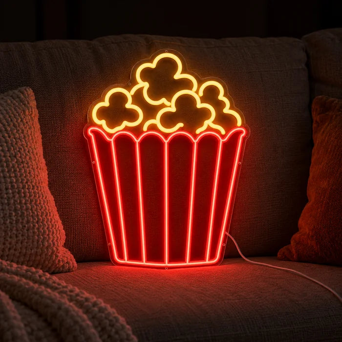 Popcorn Neon LED Schild auf einem gemütlichen Sofa zwischen Kissen und Decke