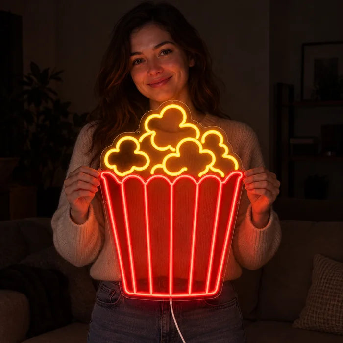 Popcorn Neon LED Schild in den Händen einer lächelnden Frau vor dunklem Hintergrund