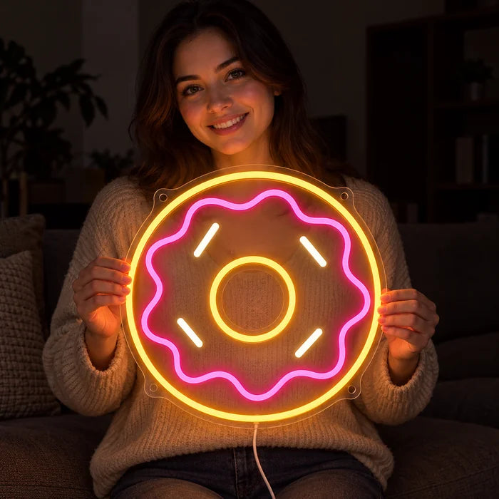 Rosa Donut Neon LED Schild in den Händen einer lächelnden Frau vor dunklem Hintergrund